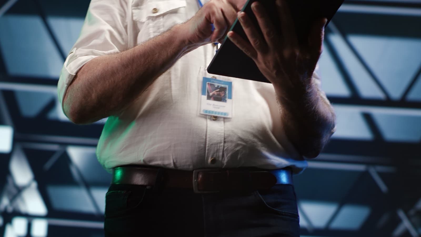 A technician with an identity badge holding a tablet inside a data centre